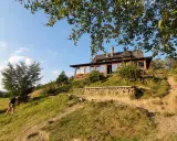 Bacówka PTTK nad Wierchomlą, drewniany dom z werandą, otoczony zielenią, zaprasza turystów na górskie szlaki.