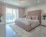 Elegancka, nowoczesna sypialnia glamour w pudrowym różu. Miękkie tkaniny, kryształowy żyrandol i bukiety róż tworzą luksusową atmosferę.
