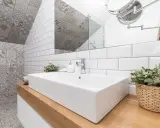 Salle de bain moderne avec lavabo rectangulaire, robinetterie chromée et un mur orné de **pose carrelage mural** patchwork gris et blanc.