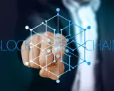 Dłoń wskazująca na sieć połączonych węzłów, symbolizującą blockchain w logistyce.