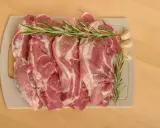 Surowe kawałki wieprzowiny z rozmarynem i czosnkiem, idealne jako jakie mięso do bigosu.