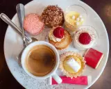 Assortiment de spécialités culinaires parisiennes : macarons, éclairs, tartellettes, verrines et café. Un délice pour les yeux et les papilles.