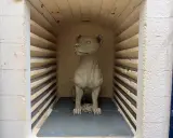 En lerhund sitter redo för bränning i en ugn.