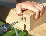 En hand skruvar i en träbit. Snobbkant eller inte, det är en rejäl ekbit som ska fogas samman.