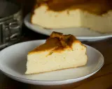 Puszysty sernik z mlekiem skondensowanym, z rumianą skórką, na talerzyku. Obok forma do pieczenia.