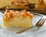Ein Stück saftiger **Mandelkuchen vom Blech mit gemahlenen Mandeln** und Zucker bestreut, auf einem Glas-Teller mit einer Gabel.