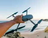Hand hält Drohne über Strand. Bereit für Aufnahmen in Deutschland, vielleicht für eine Notam-Meldung.
