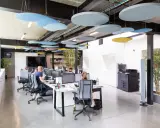 Bureau moderne avec des employés concentrés, des panneaux acoustiques colorés au plafond pour réduire le bruit au travail.