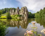 Ein idyllischer See spiegelt die imposanten Externsteine wider. Perfekt für eine entspannte Wanderung in dieser malerischen Landschaft.