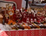 Różnorodne butelki z rakiją, w tym te w kształcie kobiecym, oferowane na targu. Co to rakija? To tradycyjny alkohol, często owocowy.