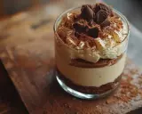 Pyszny krem do tiramisu w szklance, udekorowany bitą śmietaną, kakao i czekoladowymi kawałkami. Idealny deser na każdą okazję.