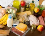 Variedad de alimentos, incluyendo frutas, verduras, pasta, latas y embutidos, que representan alimentos procesados y frescos.