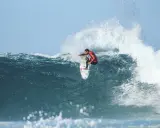 Surfer in rotem Neoprenanzug meistert eine riesige Welle beim Mauritius Surf.
