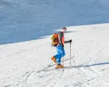 Mężczyzna na nartach z plecakiem, gotowy do podjęcia wyzwania na trasach skiturowych.