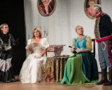 Damy w balowych sukniach i elegancki huzar na scenie.