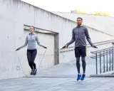 Ein Paar macht ein intensives **Springseil Workout** im Freien vor einer Betonwand.