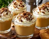 Quatre verres de café liégeois, garnis de crème fouettée et de miettes de chocolat et de biscuits.