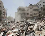 En stad i ruiner efter bombning. Dammet yr bland bråte och förstörda byggnader. Människor letar bland resterna, en påminnelse om krigets lagar och dess konsekvenser.