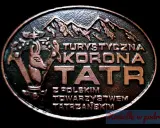 Okrągły medalion z napisem "Turystyczna Korona Tatr" i wizerunkiem kozicy. Symbolizuje zdobywanie szczytów i piękno Tatr.