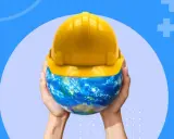 Mains tenant la Terre coiffée d'un casque jaune, symbolisant la sécurité et la réglementation des locaux de travail à l'échelle mondiale.