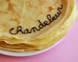 Une pile de crêpes dorées, décorées avec du chocolat formant le mot "Chandeleur". Un délice pour célébrer qu'est-ce que la Chandeleur.