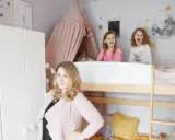 Wesołe dziewczynki w łóżku piętrowym w pokoju dla rodzeństwa. Mama uśmiecha się obok.