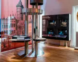 Utställning på ekonomiska museet med en stor illustration av en stad, en skulptur av en ängel och interaktiva displayer.