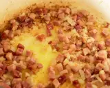 Guisantes con jamón y cebolla dorándose en una sartén con aceite. Un plato tradicional español.