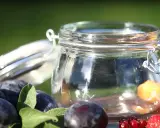 Ein Glas mit frischen Pflaumen und Beeren, bereit für Marmelade. Vorsicht bei der Zubereitung, um Botulismus zu vermeiden.