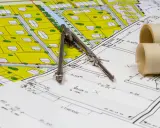 Plan zagospodarowania przestrzennego z zaznaczoną obowiązującą linią zabudowy, cyrkiel i zwoje dokumentacji.