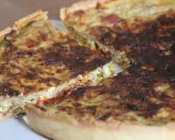 Une part de quiche poivron feta dorée, avec des morceaux de poivrons colorés et de feta crémeuse dans sa garniture.