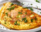 En gyllene omelett, perfekt för ett snabbt omelett recept, toppad med färsk persilja och en nypa salt.