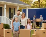 Famille souriante devant sa nouvelle maison, entourée de cartons. Des déménageurs chargent un camion, signe qu'ils sont en train d'organiser leur déménagement.