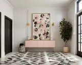 Elegancki hol z czarnymi drzwiami, geometryczną podłogą i abstrakcyjnym obrazem w sztukaterii. Różowa komoda i roślina dodają koloru.