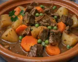 Un reconfortante plato de carne guisada con trozos de ternera tierna, patatas, zanahorias y guisantes en una rica salsa.
