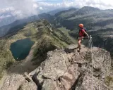 Escursionista in cima a una cresta rocciosa con vista sui laghi di Bombasel e sulle montagne circostanti.