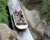 Bootsfahrt auf einer Wildwasserbahn, die durch eine üppige, grüne Landschaft führt. Die Menschen lachen und genießen die Fahrt auf der Isla Mágica.