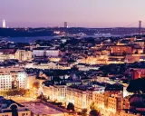 Lichter der schönsten Stadt Portugals, Lissabon, funkeln bei Dämmerung. Cristo Rei Statue und Ponte 25 de Abril Brücke im Hintergrund.
