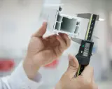 Messung eines Kunststoff-Flachprofils mit einem digitalen Messschieber. Die Präzision ist entscheidend für die Qualität.