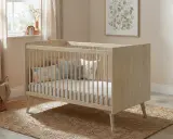 Cuna de madera clara con barrotes, colchón y cojines decorativos. Las medidas cuna son ideales para un cuarto infantil acogedor.