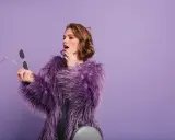 Chica con abrigo morado y maquillaje vibrante, lista para un evento.
