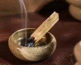 Dymiący patyczek palo santo w ceramicznej miseczce. Zastanawiasz się, palo santo co to? To święte drzewo używane do oczyszczania przestrzeni.