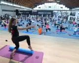 Allenamento di gruppo alla fiera dello sport Rimini, con istruttrice e partecipanti su tappetini.