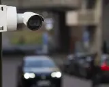 Cámara de seguridad blanca montada en poste, capturando el tráfico con su sensor global shutter.