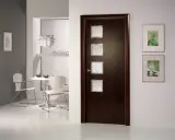 Puerta wengue con marcos de cristal. Paredes claras y un rincón de comedor moderno.