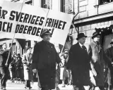 Män i hatt och rock marscherar med en banderoll: "För Sveriges frihet och oberoende!". En bild som speglar socialdemokraterna historia.