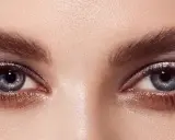 Ojos con un cautivador maquillaje con sombras azules y plateadas, realzados por pestañas largas y definidas.