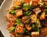 Chrupiące kostki tofu z warzywami i kaszą na talerzu.