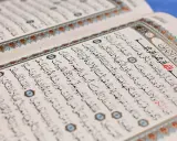 Ein aufgeschlagenes Korankonvolut mit arabischer Schrift und dekorativen Rändern. Es erinnert an die Lehren des Islams und die Geschichten von Jinn.