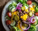 Leckerer Cheeseburger Salat mit Hackfleisch, Käse, Gurken, Tomaten und Zwiebeln auf knackigem Salatbett.